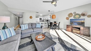 Ein modernes Wohnzimmer mit grauem Sofa, einem Couchtisch und einem TV-Bereich mit Holzschrank.