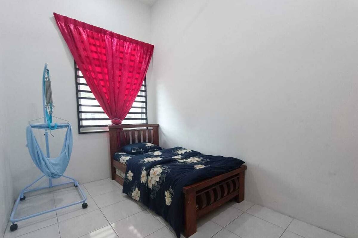 Een slaapkamer met een bed, een raam met rode gordijnen en een blauwe brancard.