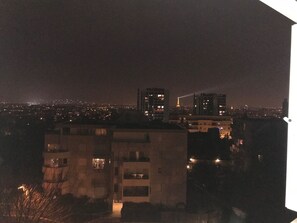 Une vue nocturne d’une ville, avec des bâtiments et une tour illuminée au loin.