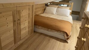 A bedroom with a wooden bed, a wooden wardrobe, and a wooden dresser. - Corniche A19 Studio mezzanine 650m from ski slopes (MORZINE)