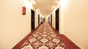 A long, narrow hotel corridor with patterned carpet, doors on both sides, and overhead lighting. - Al Muteb Suites Al Qassim (Buraydah)