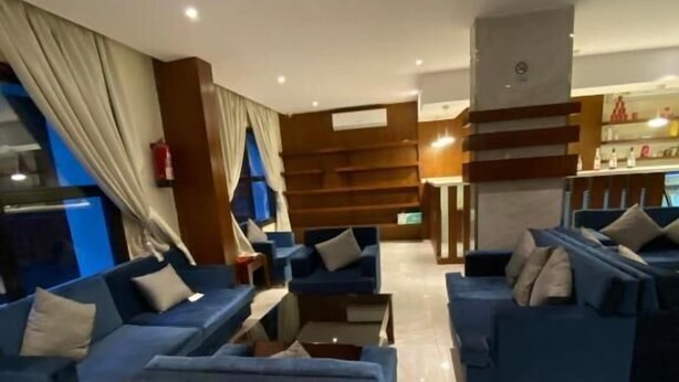 A modern hotel lobby with blue sofas, a coffee table, and a wooden reception desk. - Al Muteb Suites Al Qassim (Buraydah)