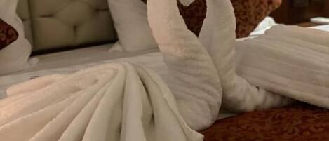 Un lit agrémenté d’une serviette pliée en forme de cygne et d’un plaid à motifs.