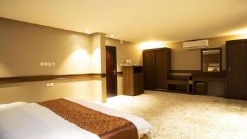 A hotel room with a bed, a desk, a wardrobe, and a mirror.