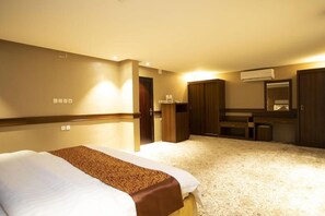 A hotel room with a bed, a desk, a wardrobe, and a mirror.
