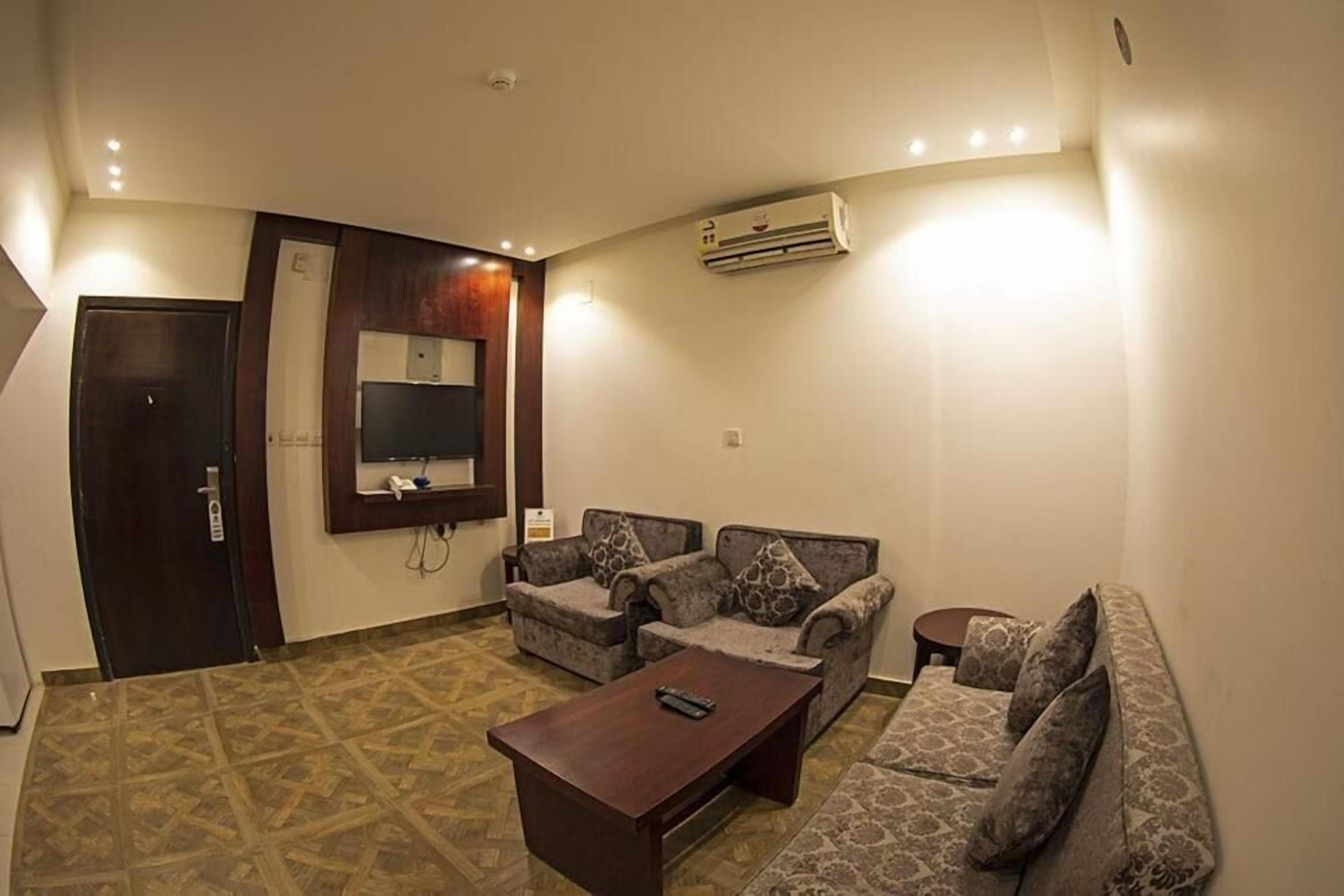 A living room with a sofa set, a coffee table, a TV, and an air conditioning unit.