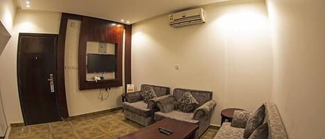 A living room with a sofa set, a coffee table, a TV, and an air conditioning unit.