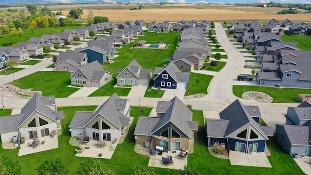 Un quartier résidentiel où les maisons se distinguent par leurs toits inclinés, leurs jardins et un espace vert central.