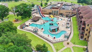 Un espace piscine doté de plusieurs toboggans et de zones de détente, entouré d’immeubles résidentiels.