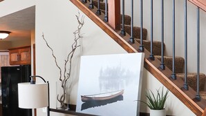 Un escalier avec des rampes en bois et un tableau représentant un bateau accroché au mur.