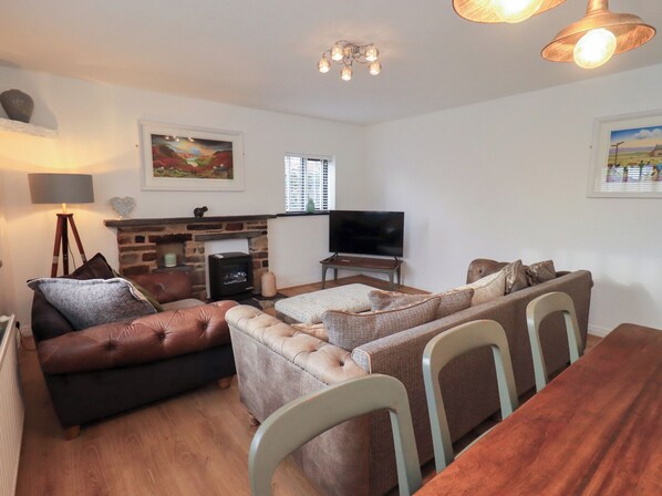 Una sala de estar acogedora con chimenea, televisor y comedor con sillas.