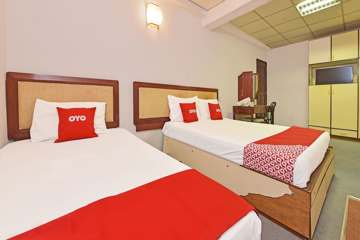 Two beds with wooden headboards, white and red bedding, and a red and white patterned blanket.