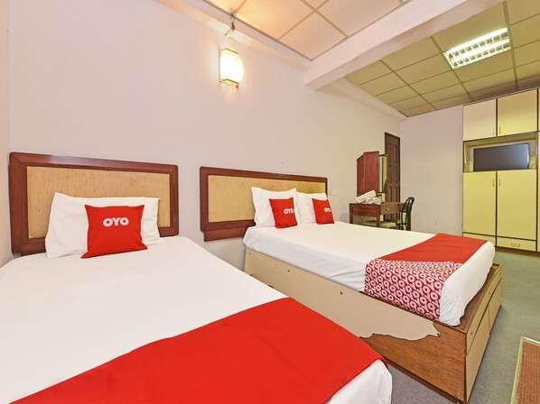 Two beds with wooden headboards, white and red bedding, and a red and white patterned blanket. - Hotel O Villa De Rose (Johor Bahru)