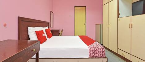 Un dormitorio con cama, escritorio de madera, armario y una puerta.