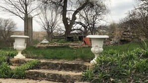 A garden with stone steps leading up to a white urn, surrounded by grass and trees. - The Lodge at the Ranch - secluded but close to Galena and golf. (Elizabeth)