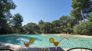 A poolside table with two martini glasses, a plate of appetizers, and a clear view of the pool and surrounding trees. - two-room apartment with pool 200mt from the sea (Santa Margherita di Pula)