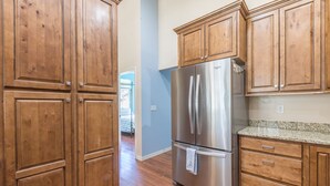 Una cocina con armarios de madera, un refrigerador de acero inoxidable y una encimera de granito.
