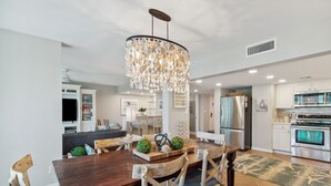 A modern kitchen with a central island, stainless steel appliances, and a chandelier.
