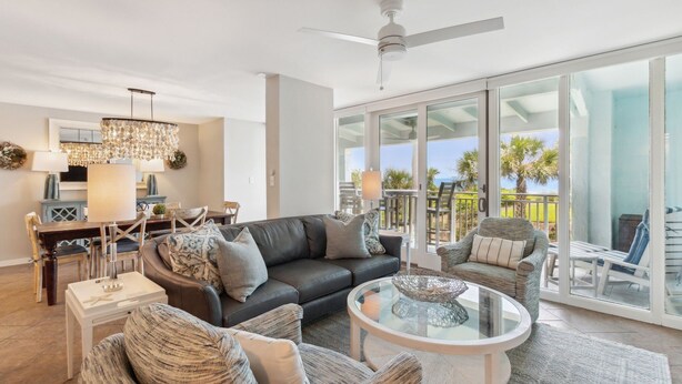 A spacious living room with a large sofa, a coffee table, and a dining area with a chandelier.
