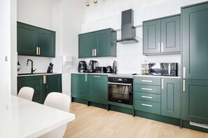 Une cuisine moderne avec des meubles de couleur verte, un plan de travail blanc et un four encastré.