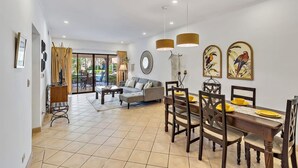 A spacious living area with a dining table, sofas, and a large window. - SR9: Luxury Condo Across the Street from Beach (Tamarindo)