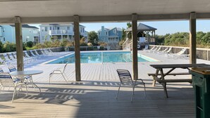 Eine Holzterrasse mit Pool, Liegestühlen und einem Tisch.