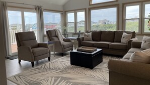 Ein geräumiges Wohnzimmer mit großem Fenster, einer Sofagarnitur und einem Couchtisch.