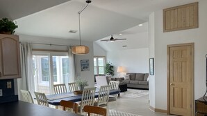 Eine moderne Küche mit Essbereich, ein Wohnzimmer mit Sofa und Lampe sowie ein Deckenventilator.