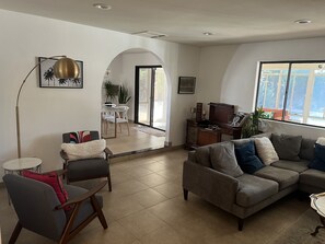 A spacious living room with a grey sofa, a coffee table, and a dining area with a white table and chairs. - Cute and Convenient - 10 minutes to downtown Palm Springs and airport (Cathedral City)