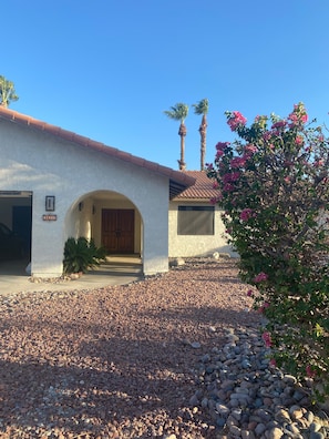 A building with a white stucco exterior, a red-tiled roof, and a gravel driveway. - Cute and Convenient - 10 minutes to downtown Palm Springs and airport (Cathedral City)