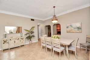 A dining area with a wooden table and chairs, a cabinet with decorative glass doors, a hanging light fixture, and a painting on the wall. - Cheerful Home in Clear Lake minutes from JSC/NASA (Houston)