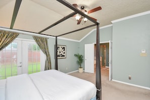 A bedroom with a four-poster bed, a ceiling fan, a potted plant, and a door leading to a hallway. - Cheerful Home in Clear Lake minutes from JSC/NASA (Houston)