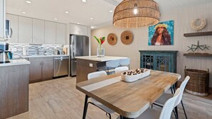 Una cocina moderna con electrodomésticos de acero inoxidable, una mesa de comedor de madera y una lámpara colgante.