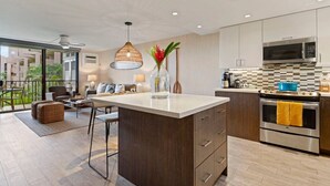 Una cocina moderna con una isla central, electrodomésticos de acero inoxidable y vistas a un balcón.