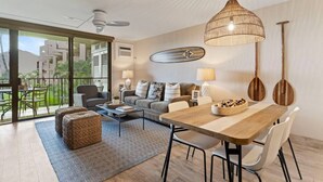 Una sala moderna con sofá, mesa de centro y mesa de comedor. Hay un balcón con vistas a edificios y zonas verdes.