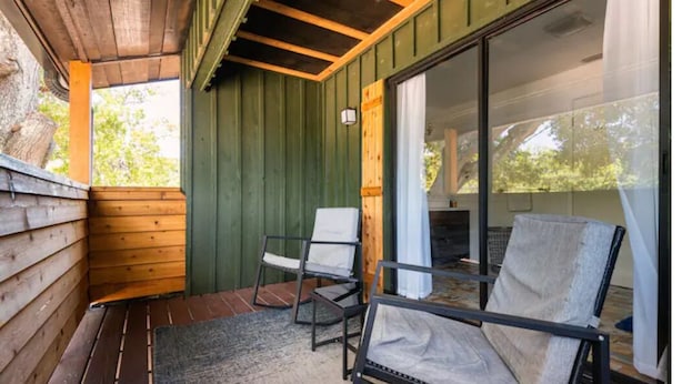 A covered outdoor seating area with wooden benches and a glass door leading to a room. - Sleeps 22 - Just min to Clearwater Beach & Indian Rocks Beach (Largo)