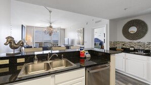 Een moderne keuken met een zwart aanrecht, een roestvrijstalen spoelbak en witte kasten.