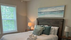 Ein Schlafzimmer mit einem hölzernen Bett, einem großen Fenster, einem Deckenventilator und einem Gemälde an der Wand.