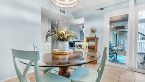 A dining area with a glass table, light blue chairs, and a centerpiece with plants. - 🏝️Short Walk 2 Gulf and Bay-Pool-Large Balcony-Boardwalk B2 (Pensacola Beach)