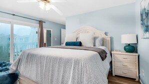 A bedroom with a bed, a nightstand, a lamp, and a ceiling fan. - 🏝️Short Walk 2 Gulf and Bay-Pool-Large Balcony-Boardwalk B2 (Pensacola Beach)