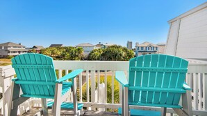 A wooden deck with two turquoise Adirondack chairs facing a white fence and a row of houses in the background. - 🏝️Short Walk 2 Gulf and Bay-Pool-Large Balcony-Boardwalk B2 (Pensacola Beach)