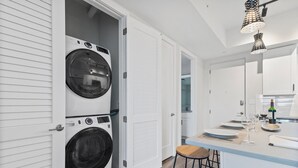 A modern kitchen with a built-in washing machine, a bar area, and a wine bottle on the counter.