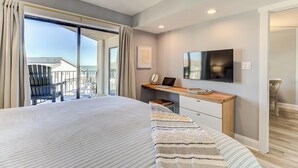 Una camera d'albergo moderna con un letto grande, una scrivania con un portatile, una televisione a schermo piatto e un balcone con una sedia.