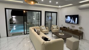 A modern living room with a sofa, chairs, a coffee table, and a TV.