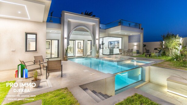 A modern house with a swimming pool, outdoor seating, and a well-lit entrance.