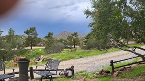 Zona salotto esterna con sedie in metallo e un tavolo, circondata da vegetazione e un vialetto sterrato.