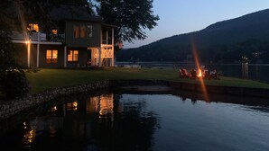 A lakeside house with a dock, a fire pit, and a view of the lake and hills.