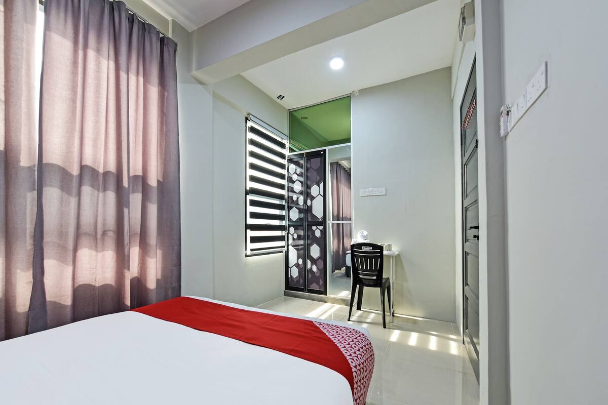 Una habitació d'hotel amb un llit, una taula de treball i una cadira.