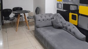 A modern living room with a grey sofa, a round table, and black chairs.