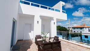 Ein modernes Gebäude mit Balkon, weißen Wänden und blauem Himmel.